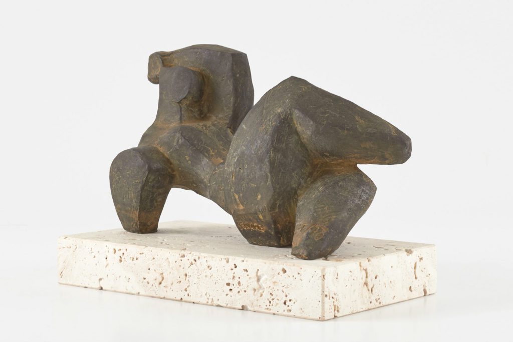 Escultura antropomorfica abstracta de una mujer recostada del artista Donaire. Pieza de bronce patinada sobre base de piedra.